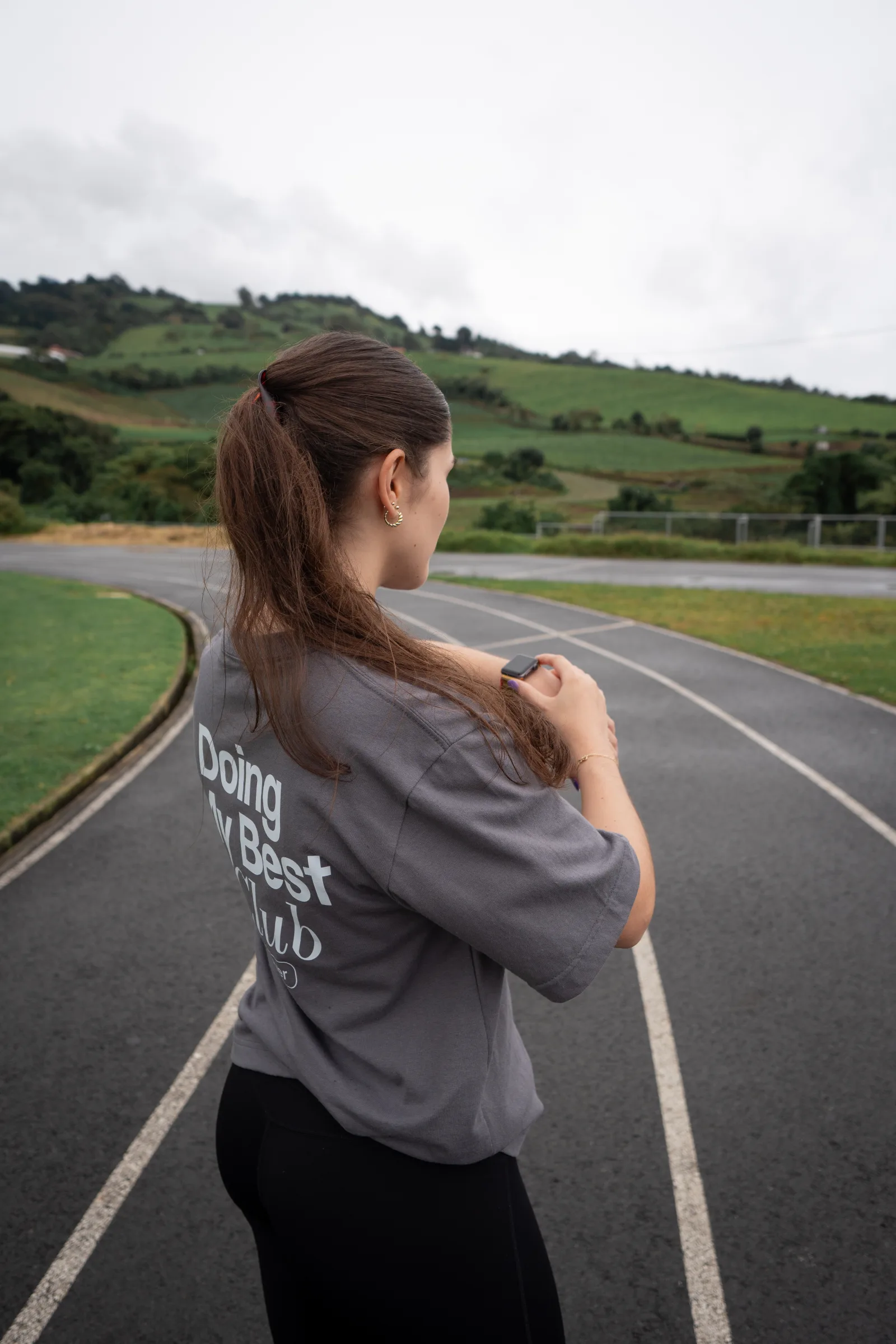 Athlete checking her watch in a gray MOVA shirt on a running track