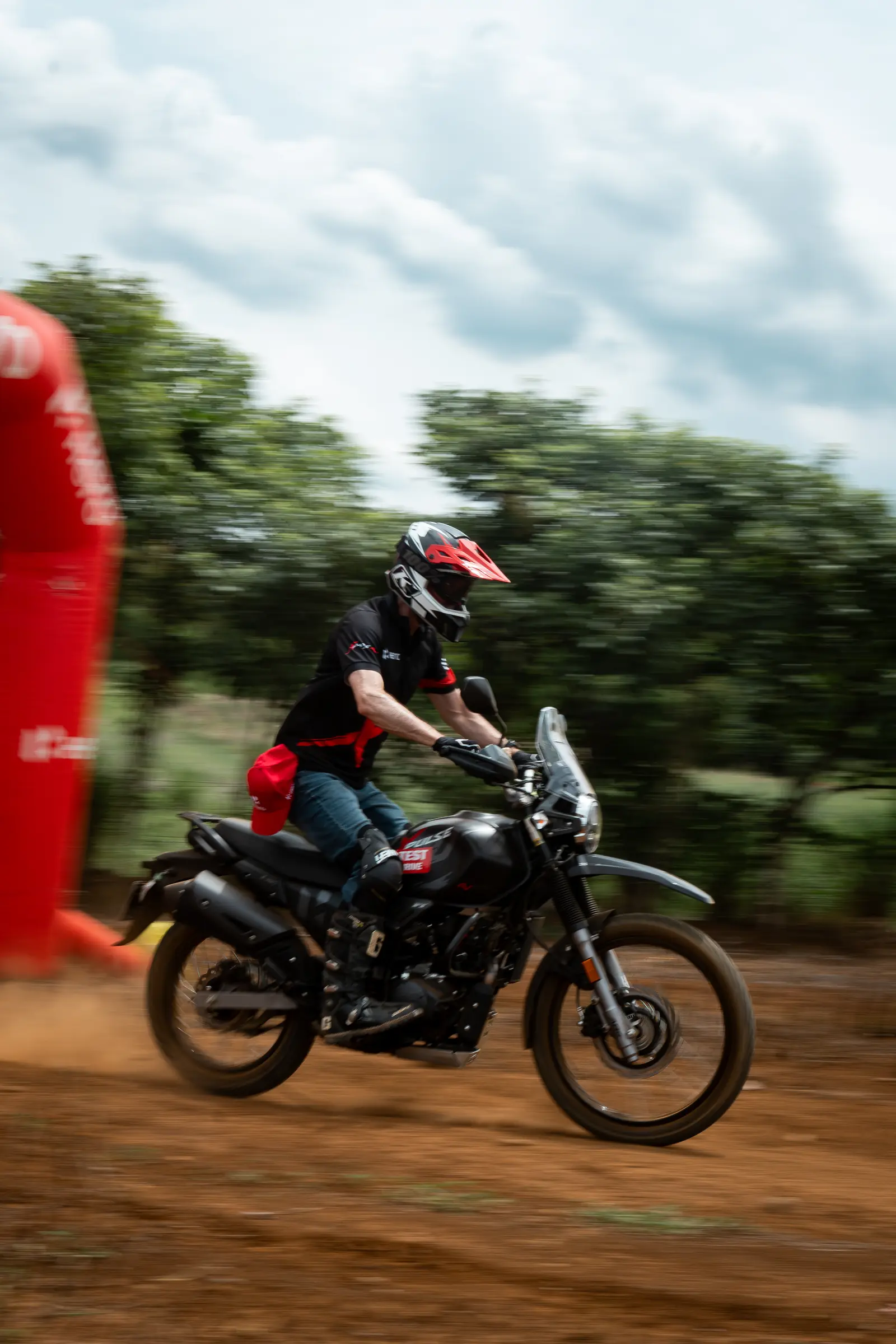 Motorcyclist riding past a red course marker during an off-road event