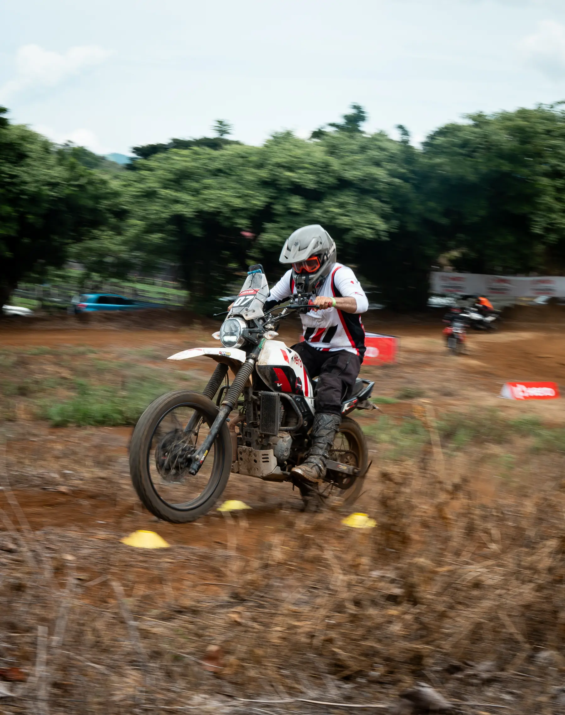 Motorcyclist leaning forward on a dirt trail with course cones