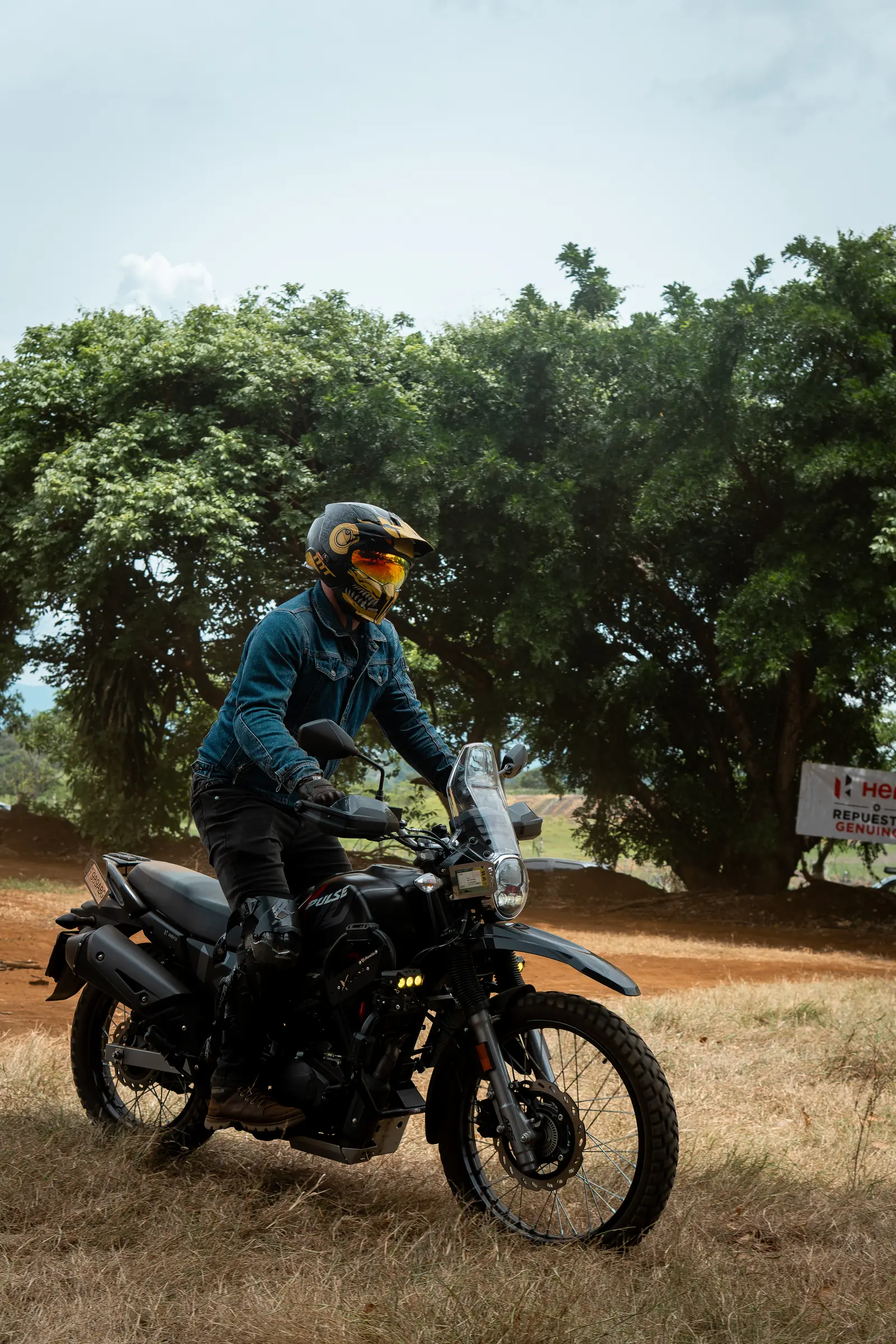 Rider standing on a black adventure motorcycle under trees